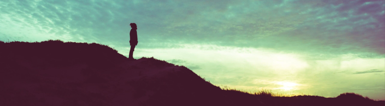 Traveler at sunset on a hill over a beach